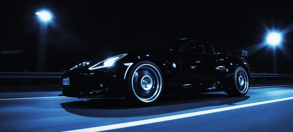 Black performance car driving at night under street lights